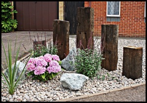 THE PEBBLES DRIVEWAY WITH SMALL WOODEN SLEEPERS CONSTRUCTION AND SOME PLANTS...